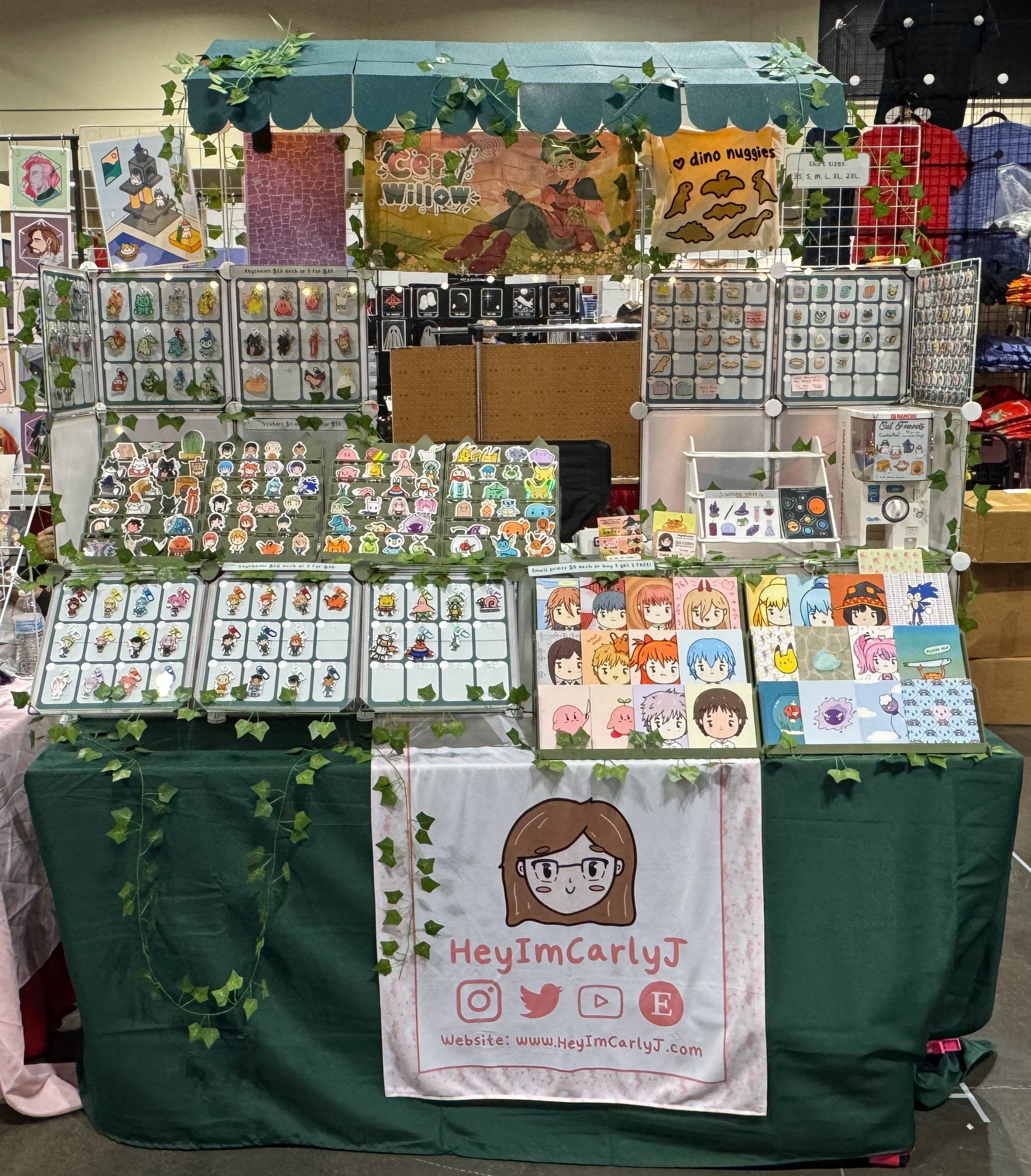 Stall with various merchandise and a sign reading 'HeyImCarlyJ' at an event.